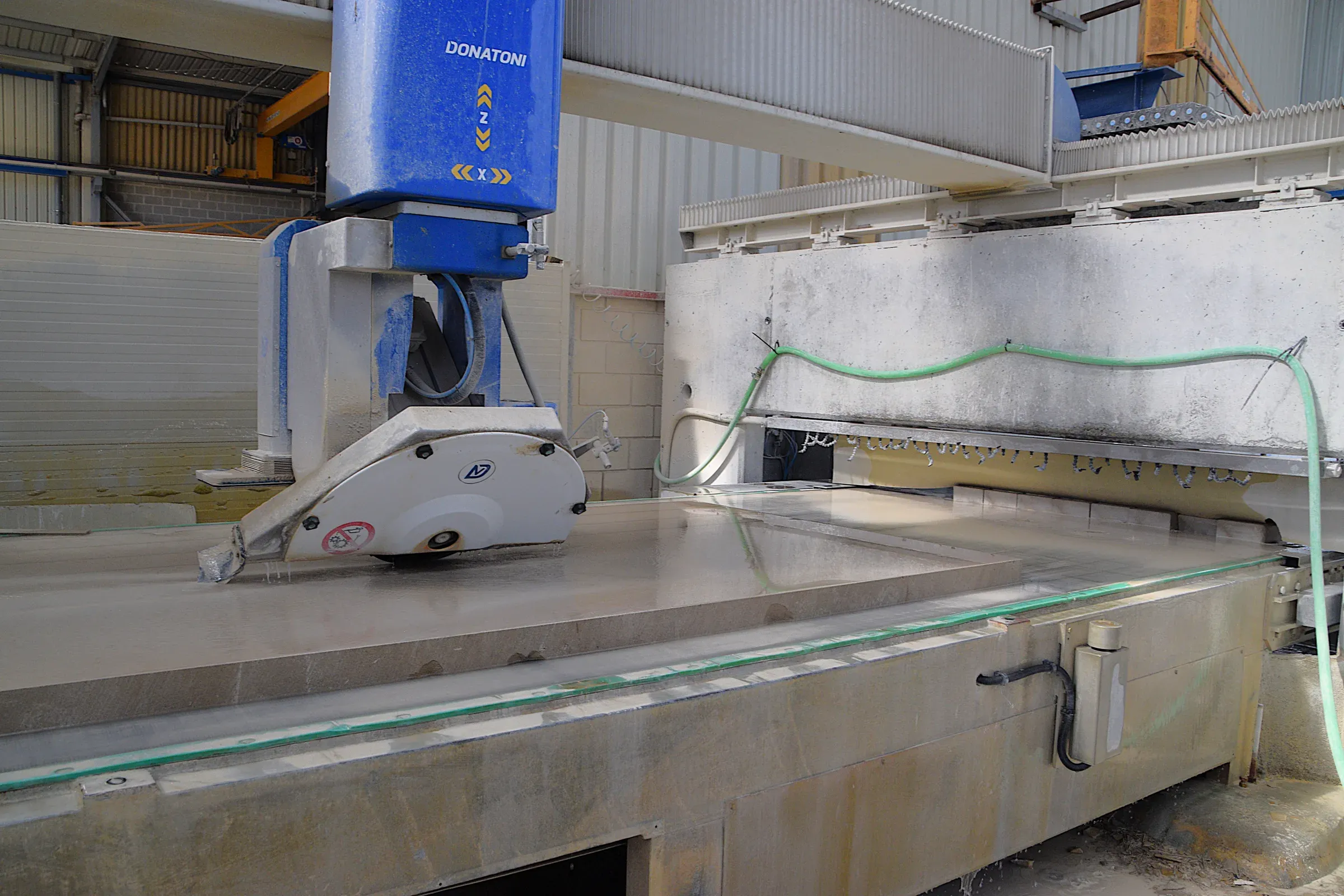 Bridge saw cutting a stone piece in the workshop